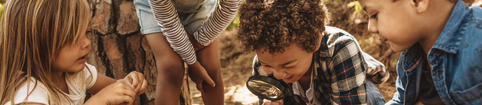 Kids exploring in forest with a magnifying glass