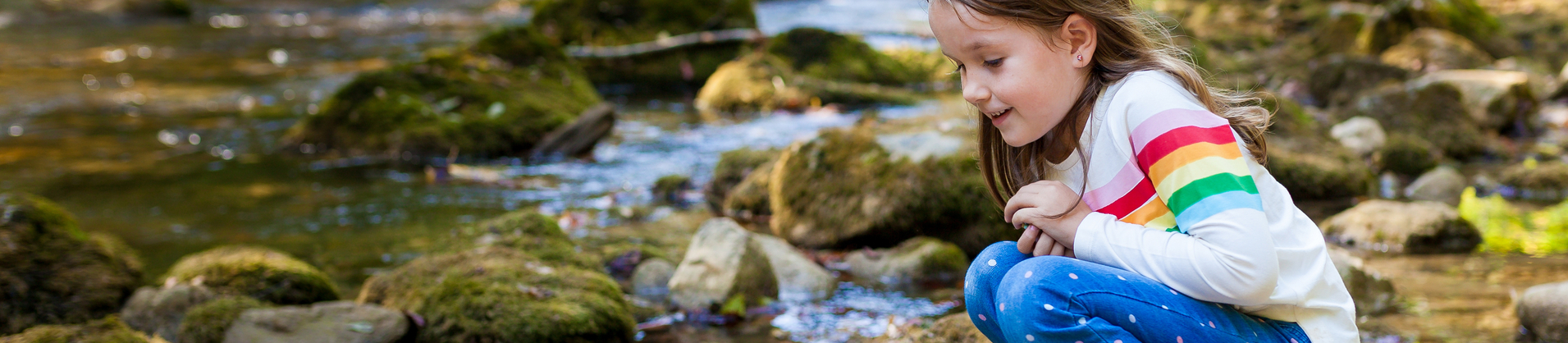 Outdoor recreation and awesome adventures with kids. A little child girl is walking along a green river in the forest in rubber boots on a warm autumn day. exploring nature, travel, family vacation.